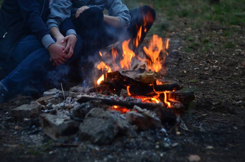 Couple warming up near a campfire